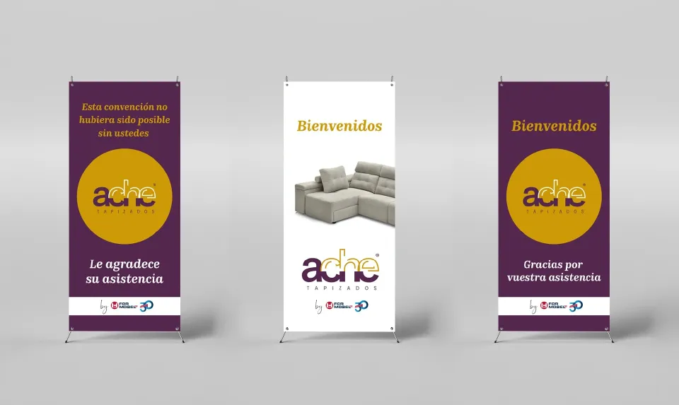 Three purple-and-mustard Ache roll-up banners, one with a grey sofa and the message 'Welcome'