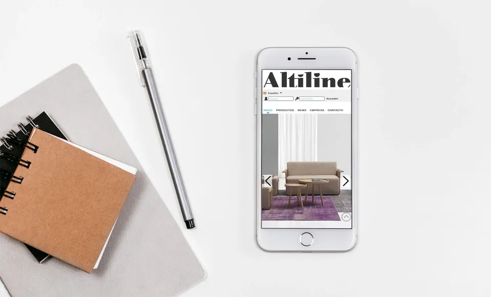 Altiline's website on a phone showing a beige sofa product page, next to a notebook and pen