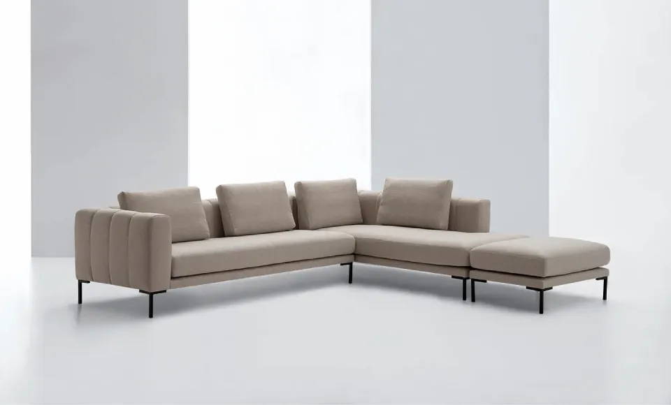 Sofá rinconera beige con chaise longue y puf a juego, fotografiado en estudio