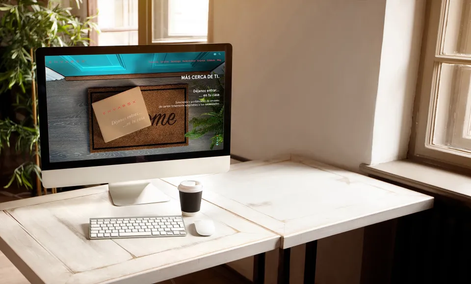 Desktop computer showing the Envabox website next to a coffee cup on a wooden desk