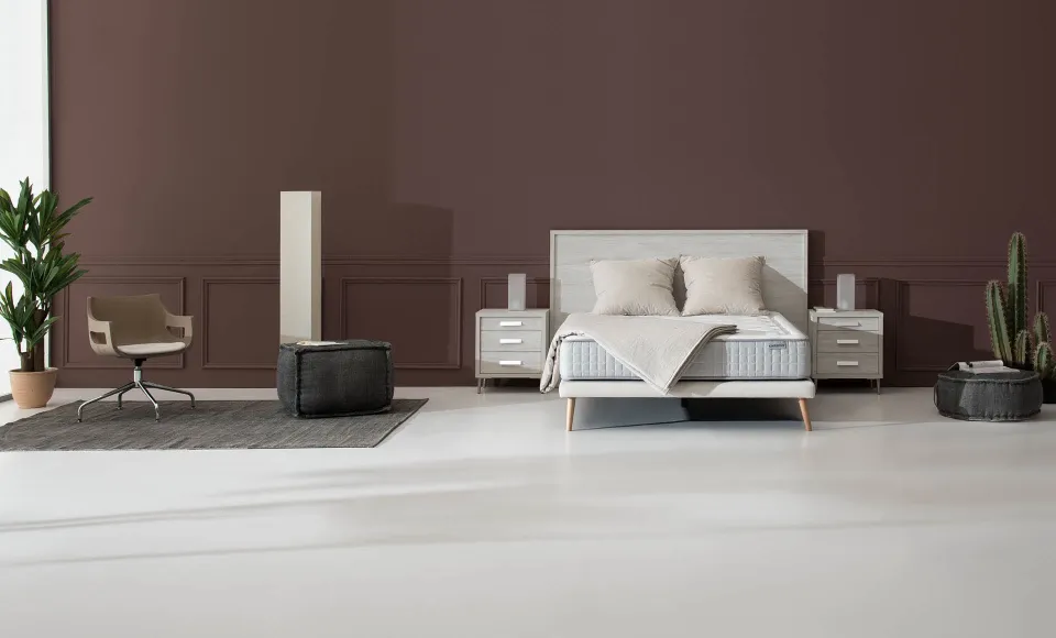 Brown-toned bedroom with a Karibian Descanso bed, an armchair and a stool