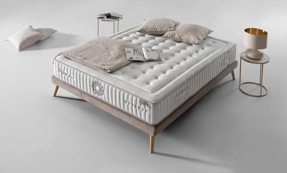 Cama con colchón acolchado crema de Karibian Descanso, cojines y mesitas doradas