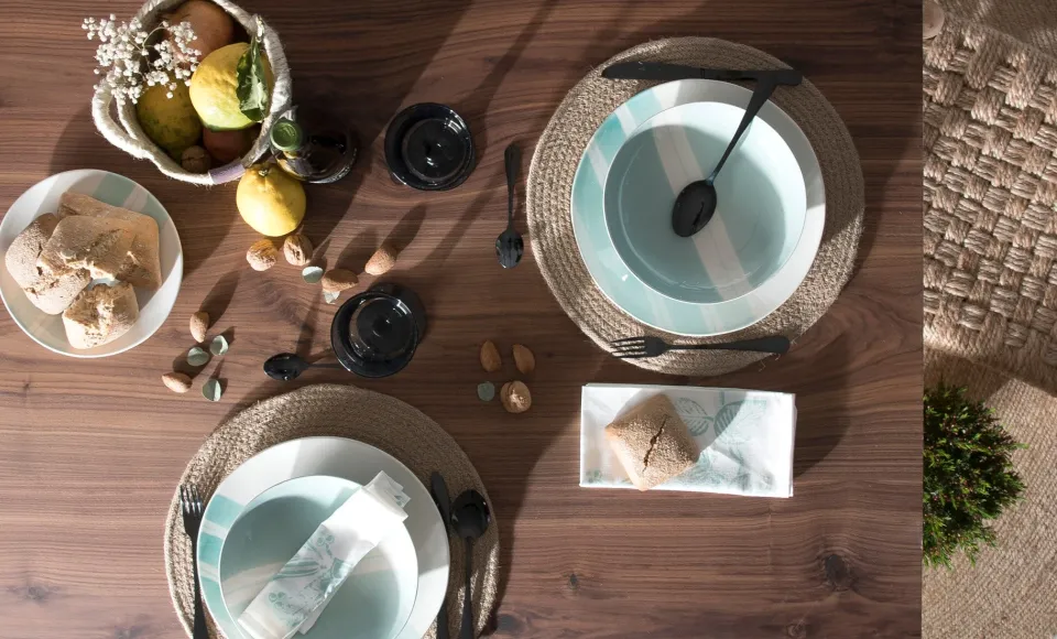 Table set with crockery, woven placemats and fruit on a wooden table