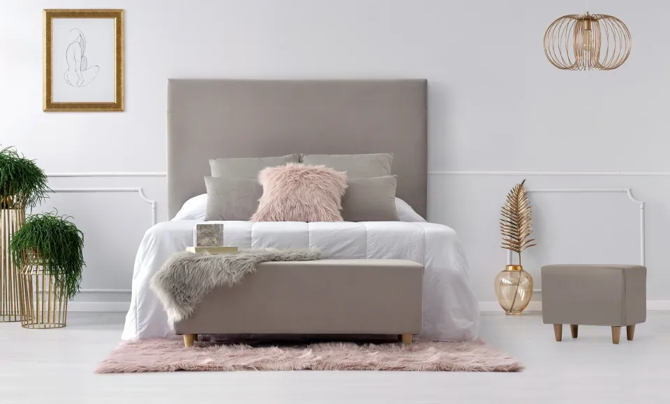 Bedroom with a beige upholstered headboard, pink cushions and gold accents