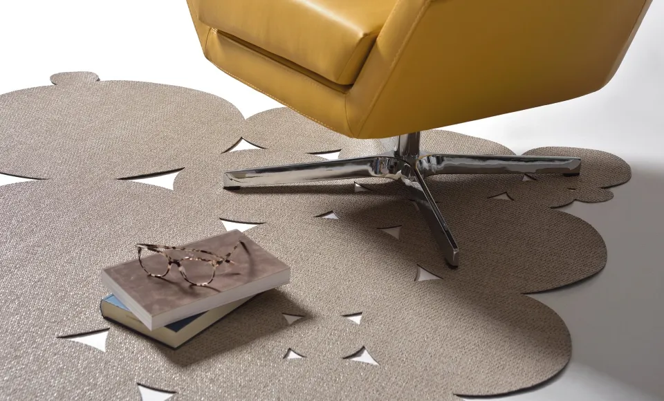 Parentesi Quadra die-cut rug beside a yellow leather armchair with a book and glasses