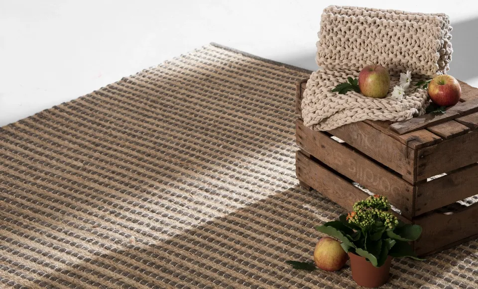 Parentesi Quadra striped jute rug with a knitted throw and apples on a wooden crate