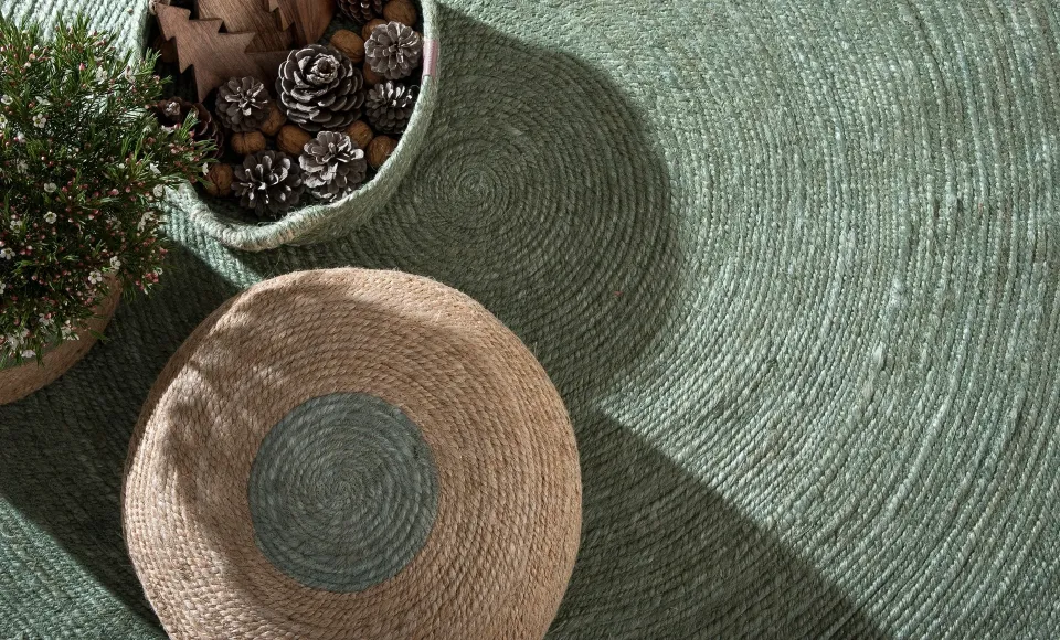 Round green rug by Parentesi Quadra with a woven basket and pine cones