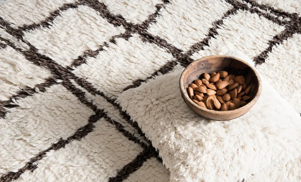 Berber-style rug with a cushion and a bowl of almonds by Parentesi Quadra