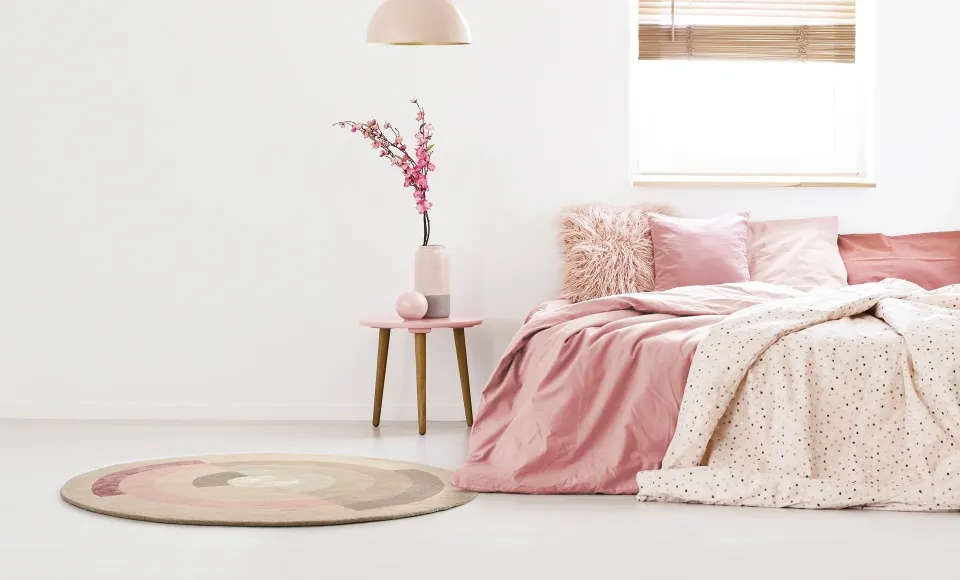 Pink-toned bedroom with a round rug and patterned bedding