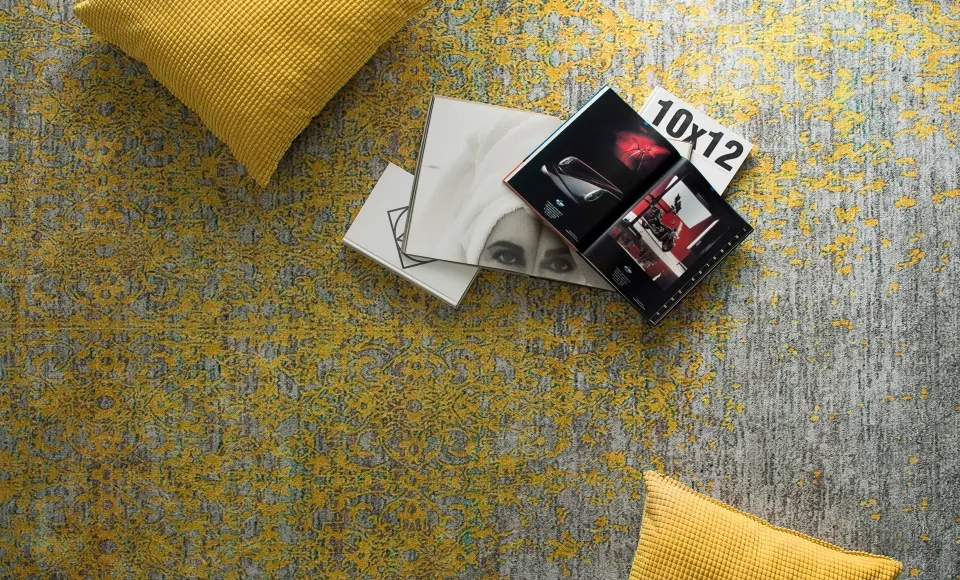Grey rug with mustard details by Parentesi Quadra next to cushions and magazines
