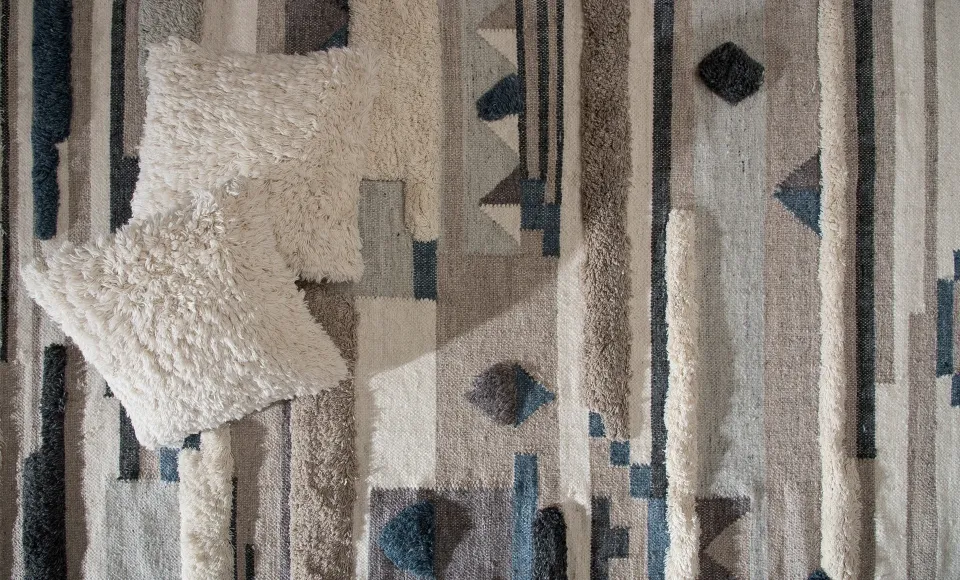 Geometric ethnic-pattern rug with a faux-fur cushion by Parentesi Quadra