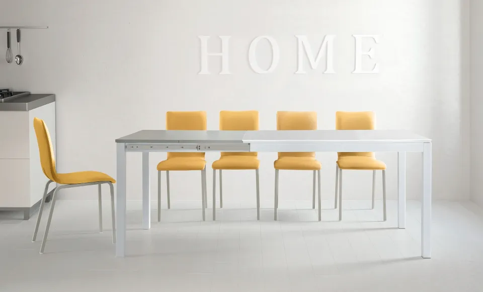 White dining room with a Tabou table and yellow chairs, HOME lettering on the wall