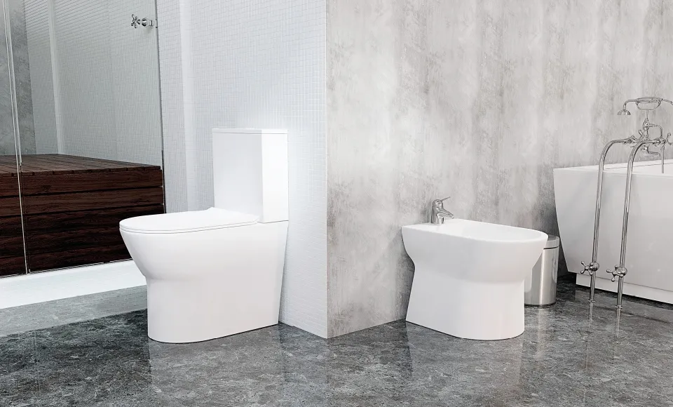 White toilet, bidet and bathtub inside a bathroom with grey marble flooring