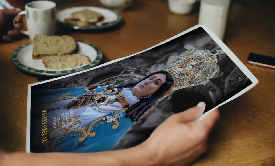 Hand holding a Valery Relax photograph of a woman wearing a veil and a jewelled headdress, on a table